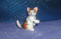 Miniature Petit chat tricolore II assis patte en l'air
